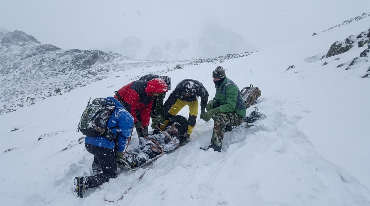 Trekkers rescuing an injured person on a snowy Himalayan trail