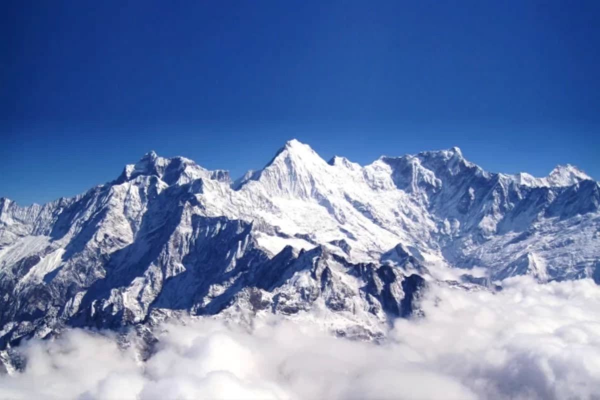 Majestic view of Mount Everest and surrounding Himalayan peaks under a clear blue sky with clouds